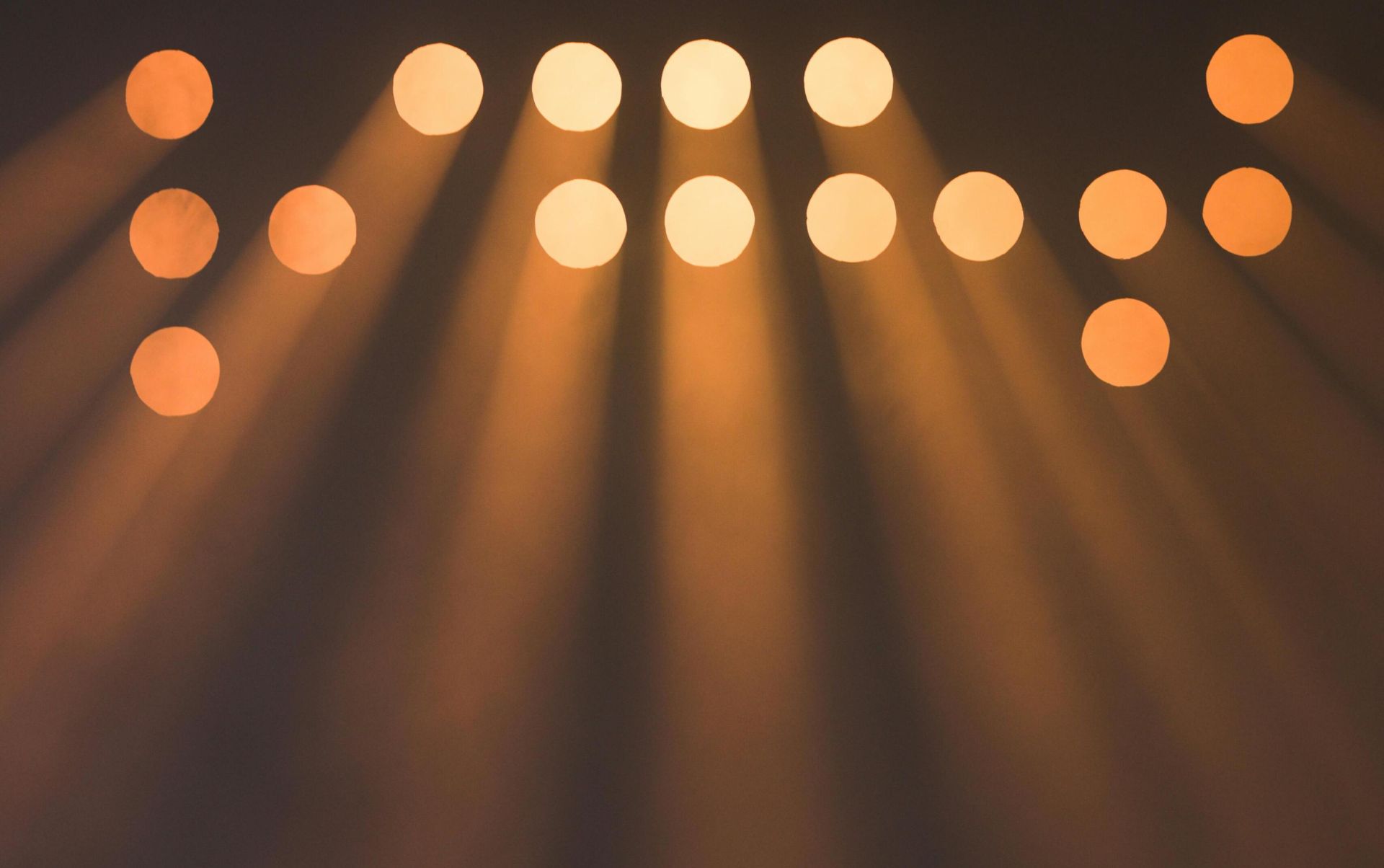Abstract image of multiple spotlights casting bright rays in darkness.